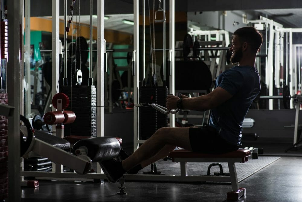 muscular sportsman training on arms machine in gym