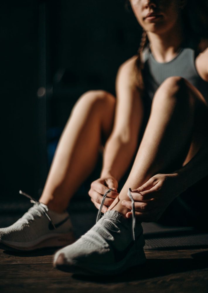 woman in white tank top and blue denim shorts sitting on black floor