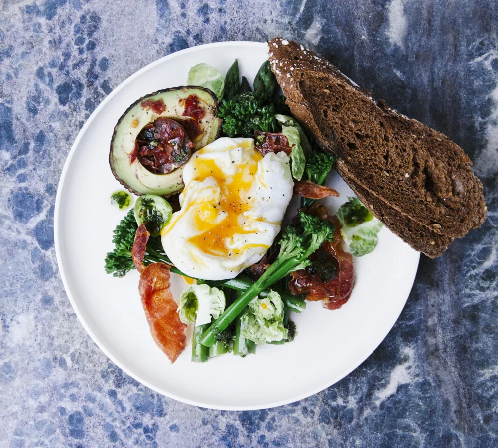Ensalada con huevo escalfado, aguacate y tomates cherry en un plato