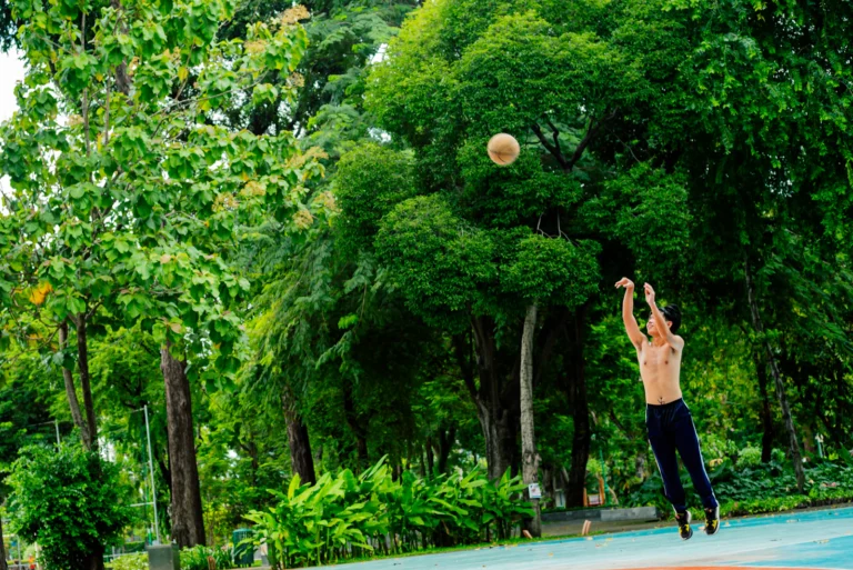 Jugador de baloncesto saltando hacia el aro en una pista exterior