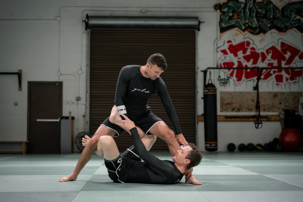 Dos practicantes de jiu-jitsu brasileño con kimono entrenando en el tatami