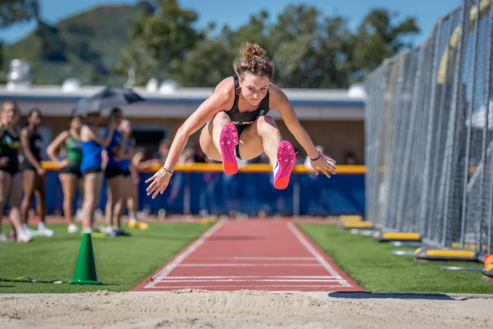 Deportista en pleno salto vertical en una pista de atletismo